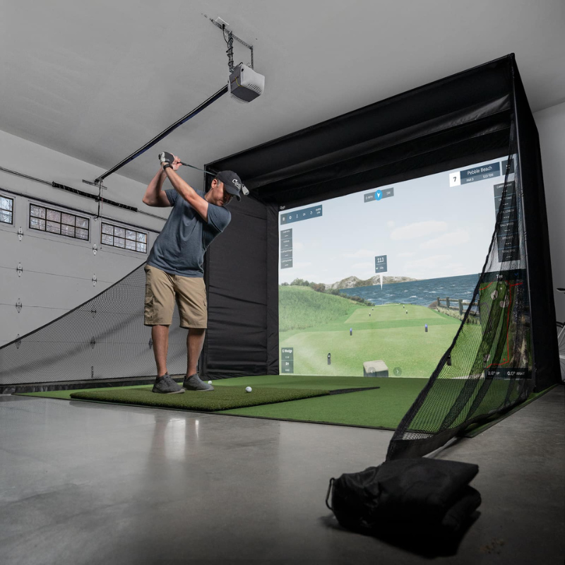 Carl's Place C-Series DIY Golf Simulator Enclosure Package with Impact Screen and a golfer hitting balls on a launch monitor.